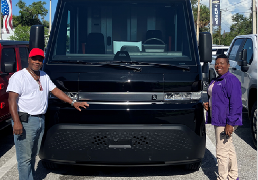 Two people in front of a BrightDrop van