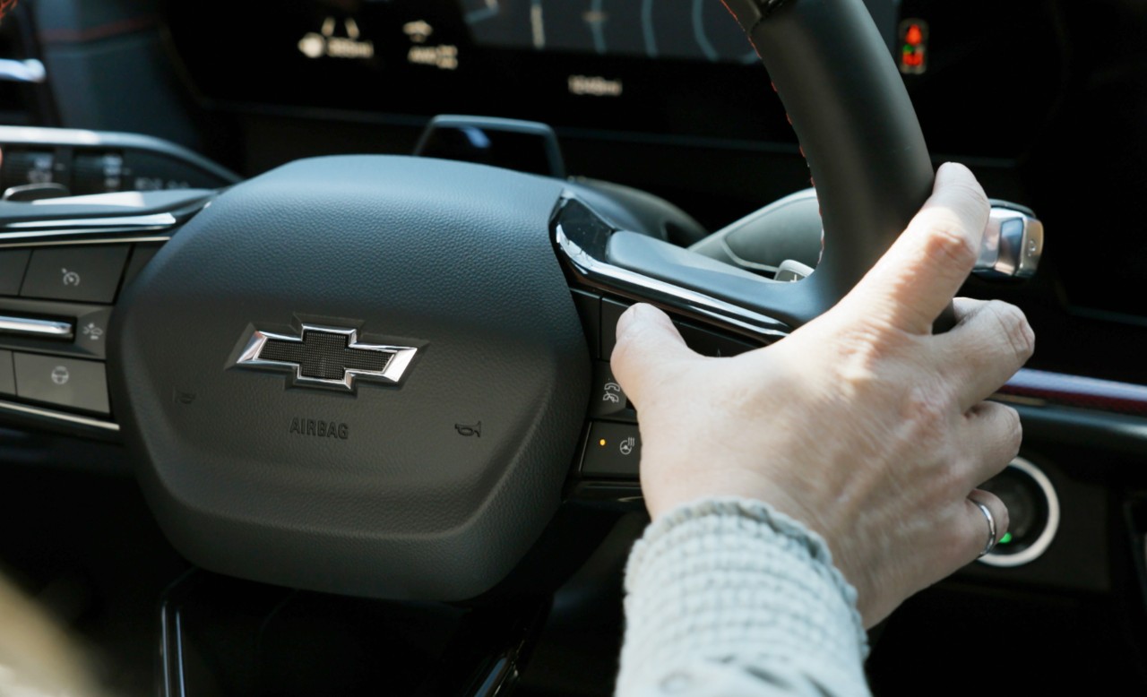 Driver using steering wheel controls in Chevrolet.