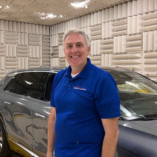 Engineer Doug Moore Standing Next to a Cadillac Vehicle in a Sound Proof Lab