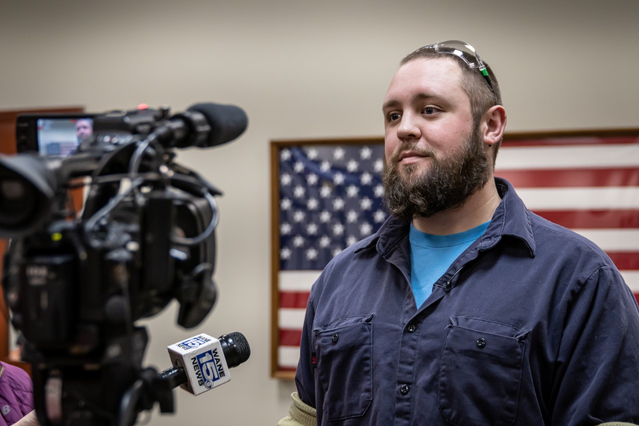 Ft. Wayne Assembly employee Sam Barker stands in front of a TV camera for an interview about Ivy Tech Community College.