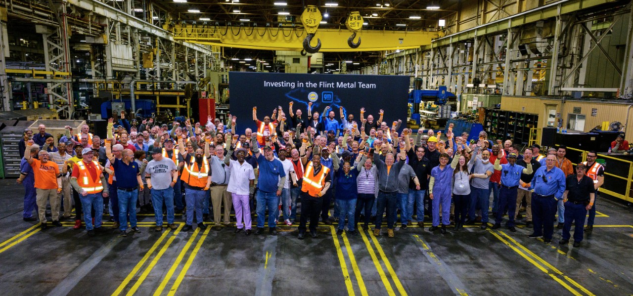 GM employees pose in front of Flint Metal Center banner.