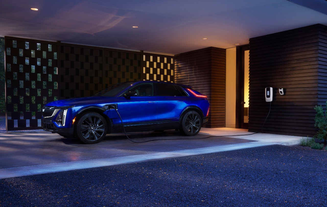 Side profile view of the Cadillac LYRIQ Sport plugged into a GM Energy charging unit.