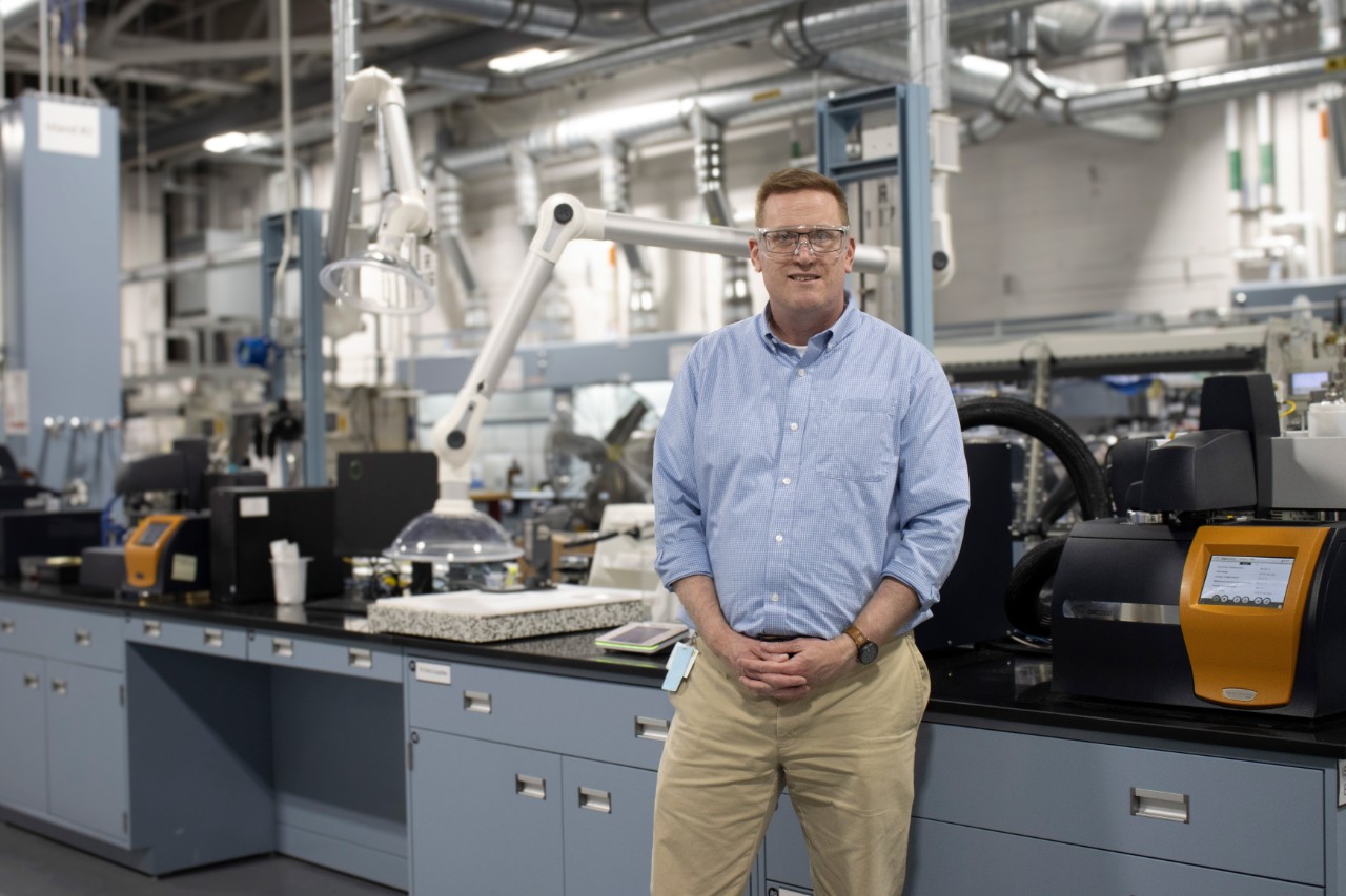 A man in a blue shirt standing in a chemistry lab.