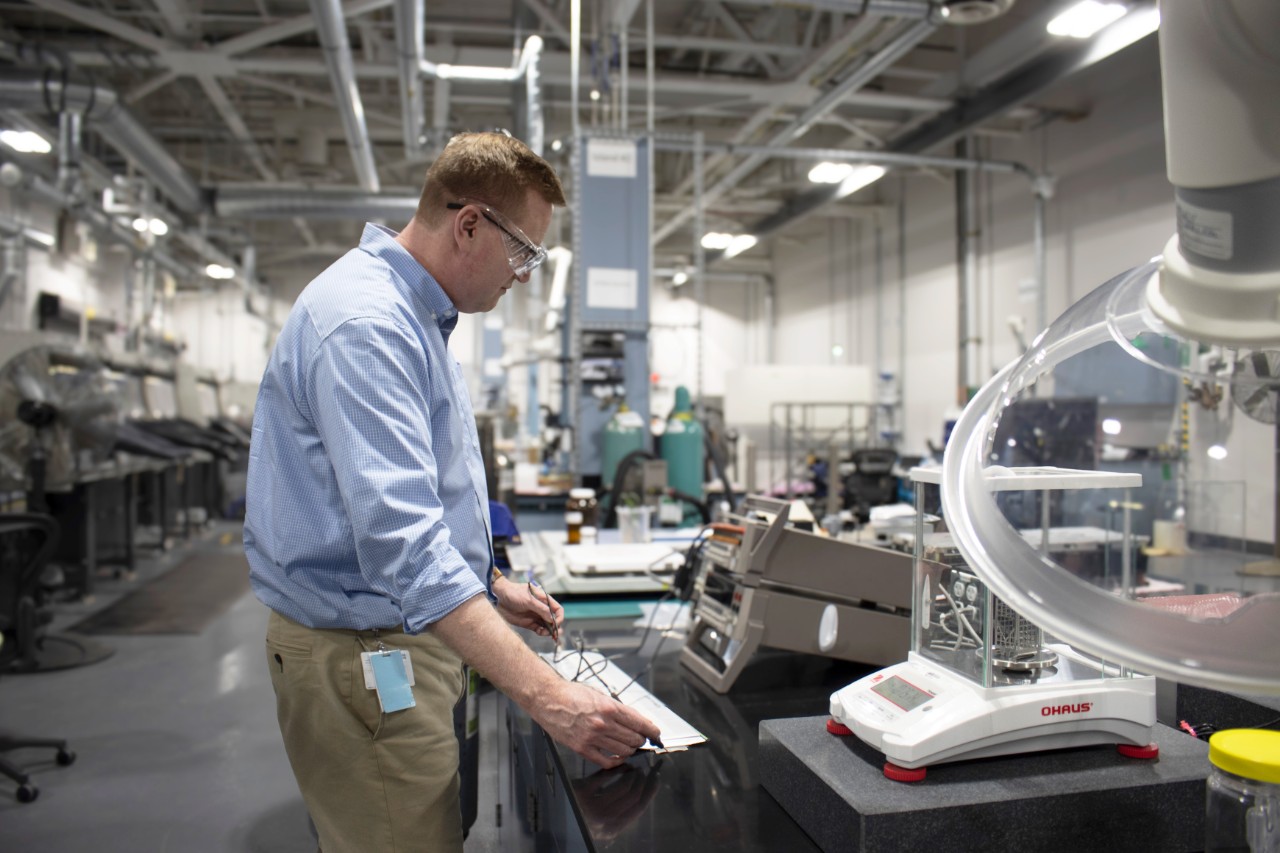 A man in a blue shirt working in a chemistry lab.