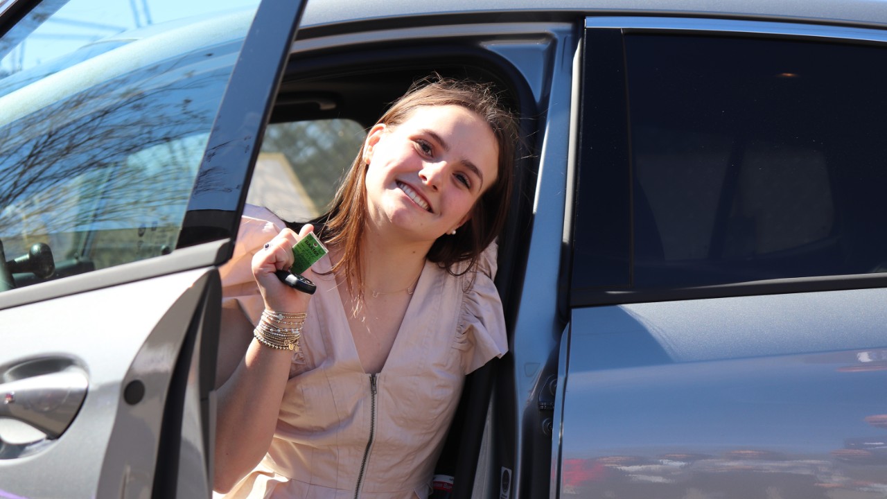 A teen smiling while sitting in a car.