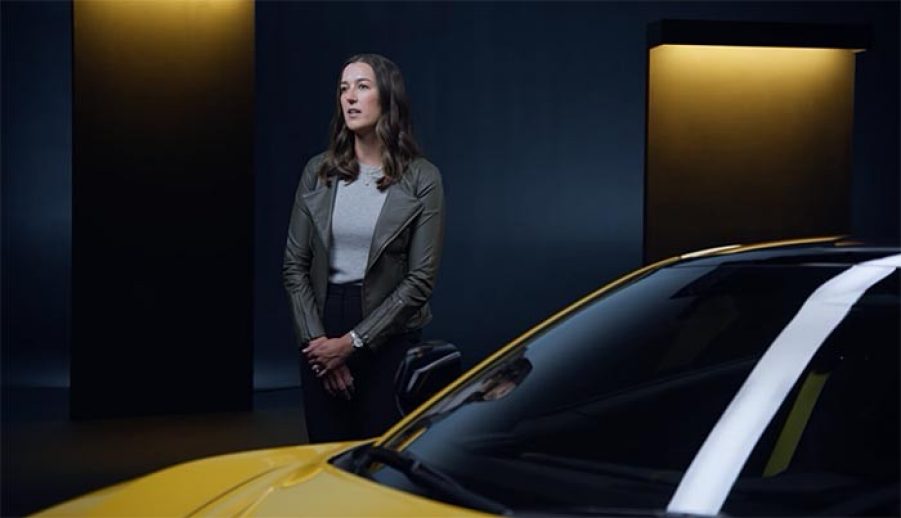 A woman standing in front of a car in a studio.