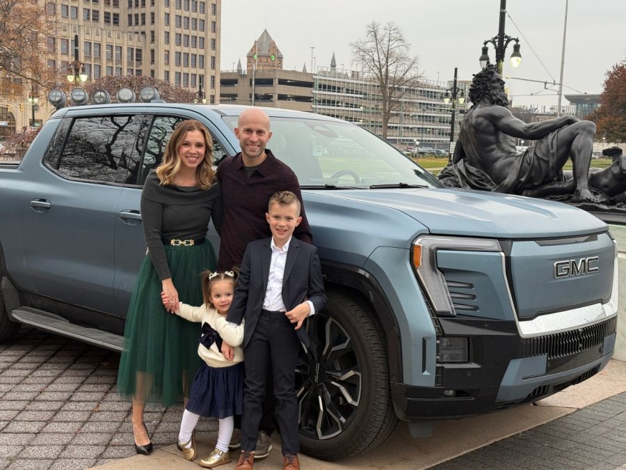 A family stands next to a pickup truck.