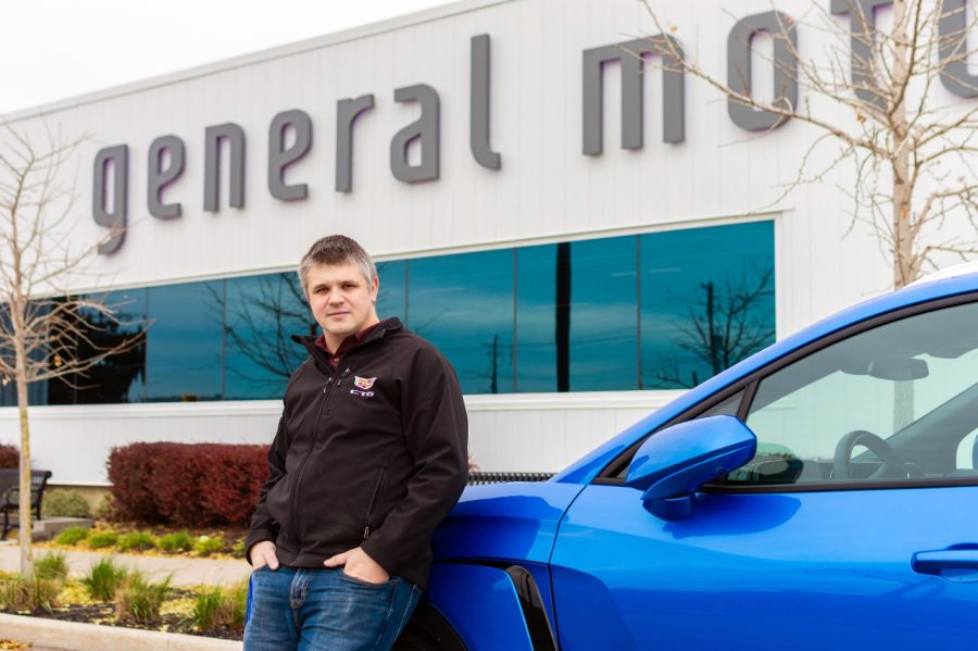 Man next to blue car outside corporate building