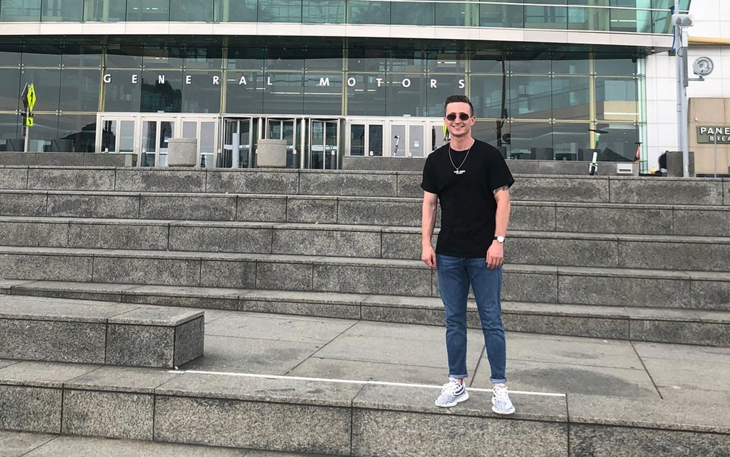 Clayton Gelfand takes a photo opportunity at GM’s Detroit Renaissance Center in 2022 A man standing on the steps of a building.