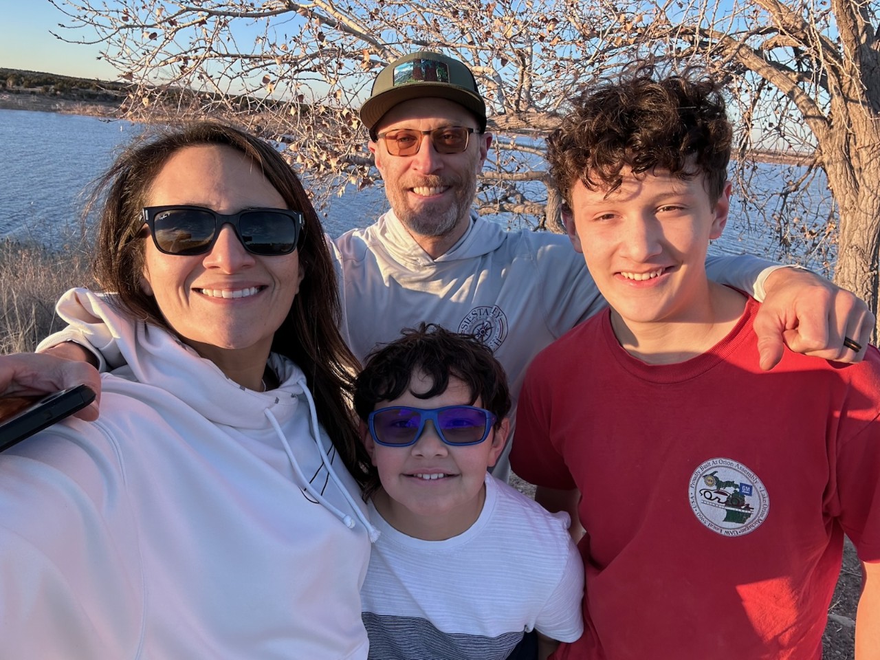 A family of four smiling at a park.