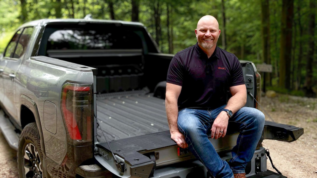 Man sitting in bed of pickup truck.