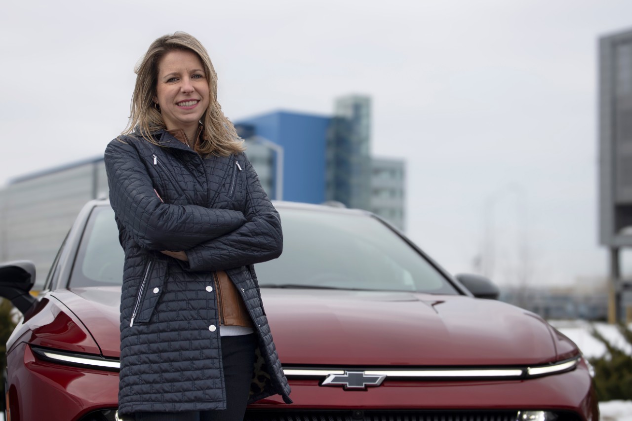 Chief engineer Kristin Cermak wears a navy jacket and stands in front of a metallic purple/gray Chevy Blazer EV.