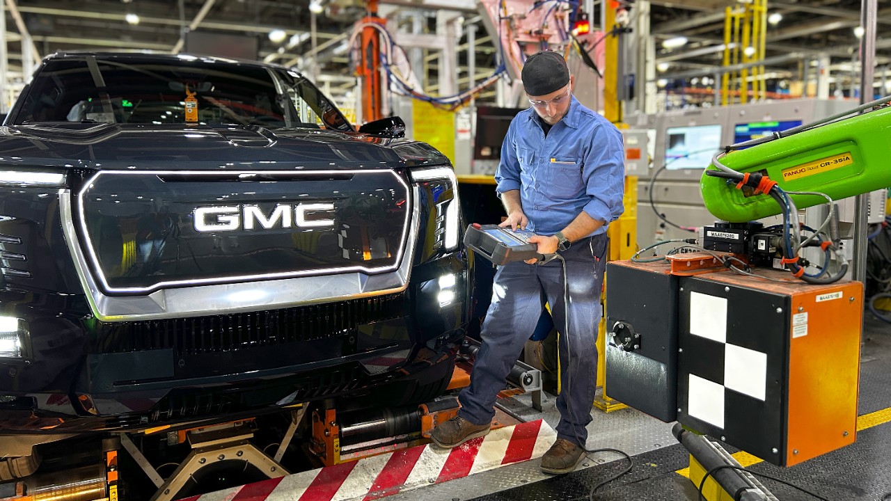 A man works on a vehicle on an assembly line.