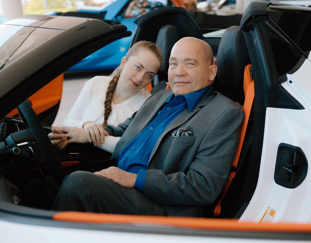 A couple sit in a white car.