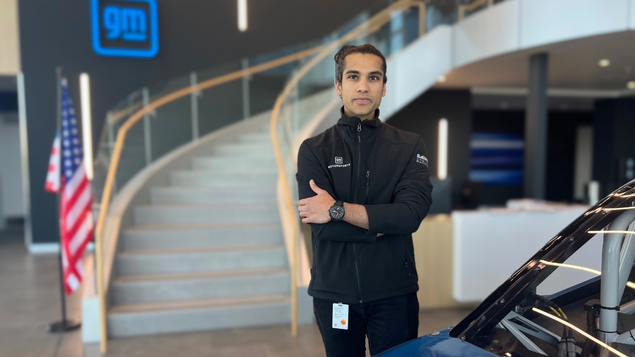 Man standing in a building lobby next to a car.
