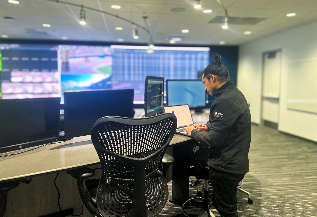 Man standing in an office in front of computer monitors.
