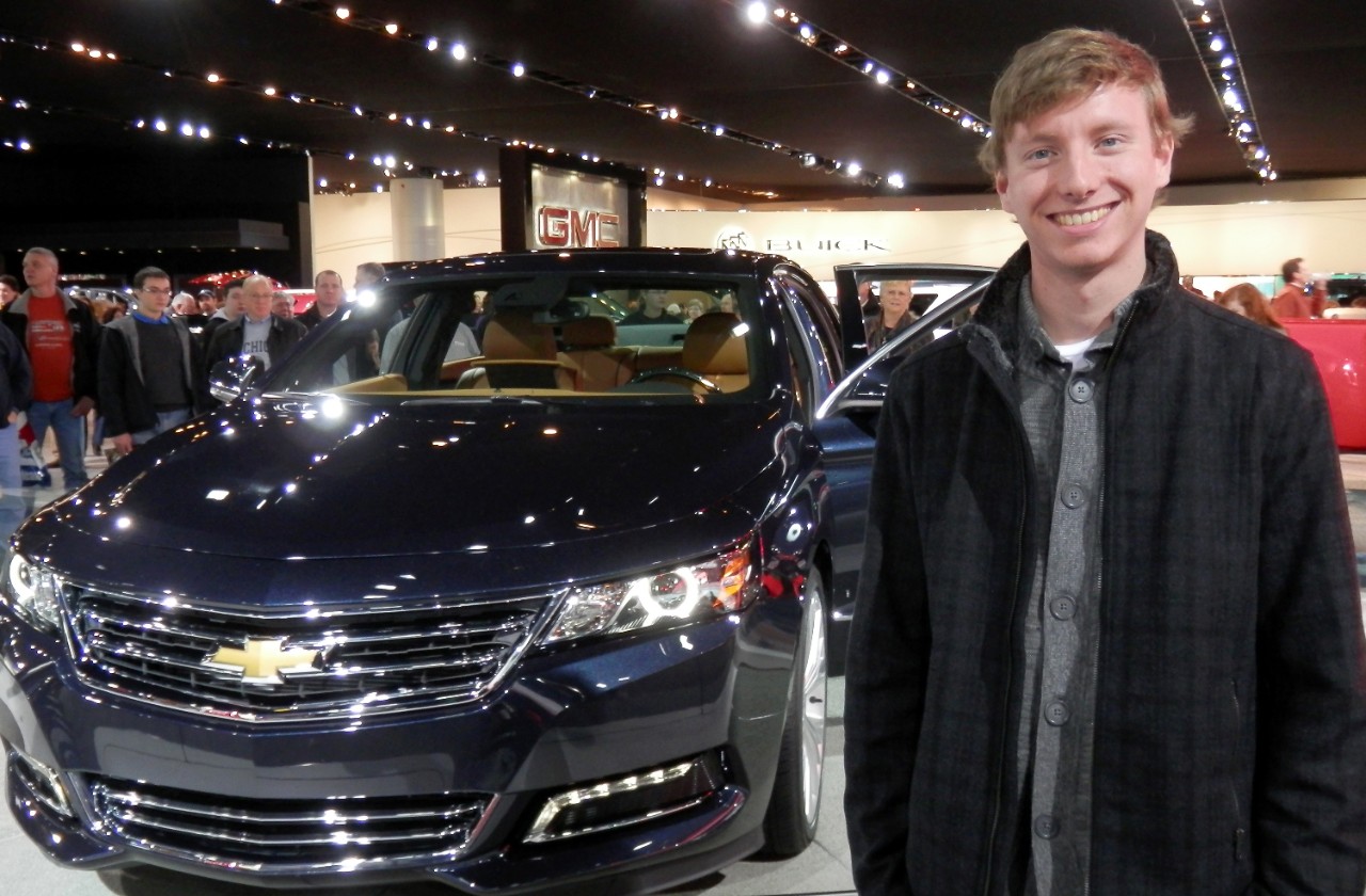 A man smiling in front of a car