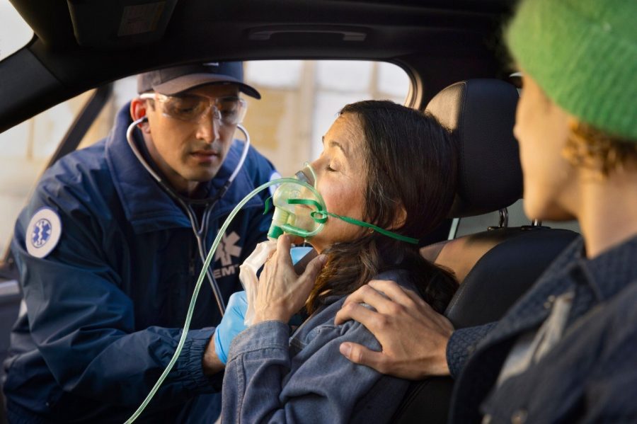 First responder provides oxygen to woman in car.