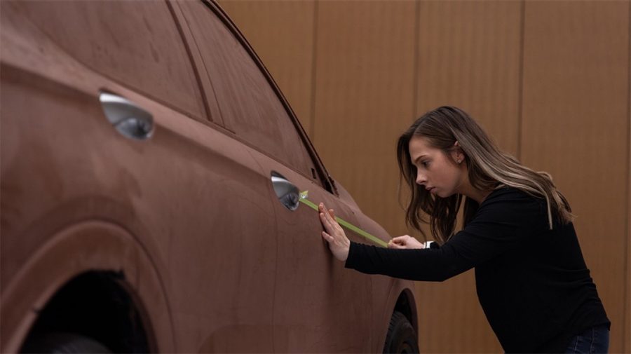Artisan working on full-size clay model car.