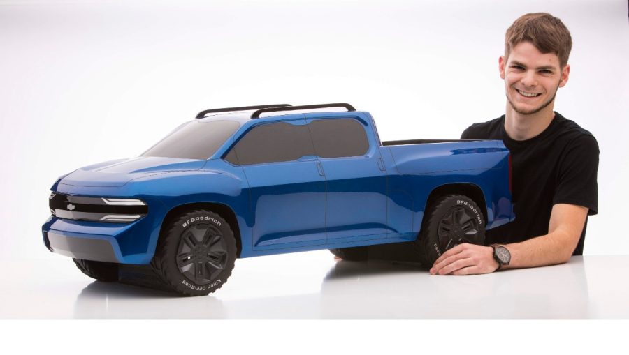Car designer posing with blue scale model truck