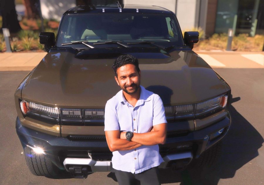 Aamir Ali leans against a GMC HUMMER EV
