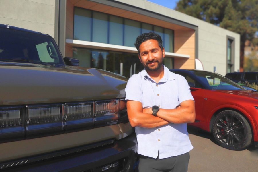 Aamir Ali leans against a GMC HUMMER EV