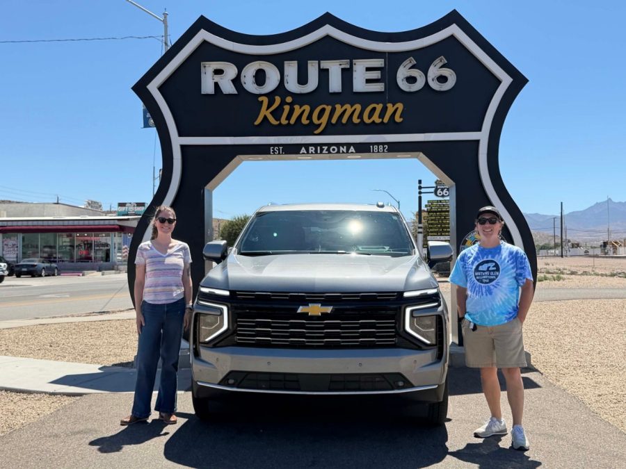 Route 66 sign with 2 people standing next to a Chevrolet Tahoe