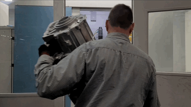Man loading transmission casing into CT scanner