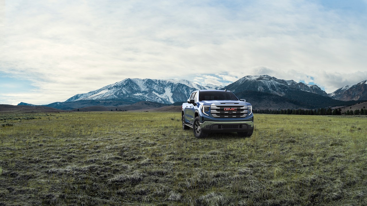 Onyx Black GMC Sierra 1500 SLE parked in an open field with mountains in the background.