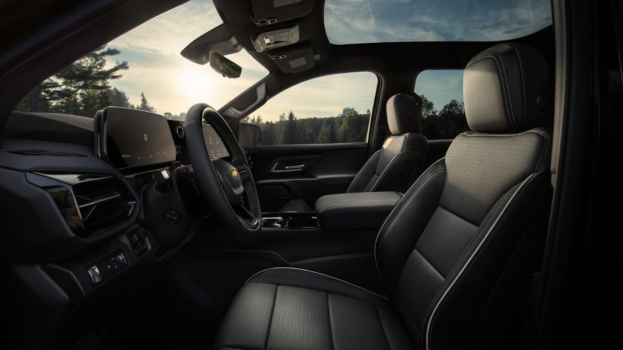 Spacious front interior of a Chevrolet vehicle featuring premium black leather seats and digital displays.