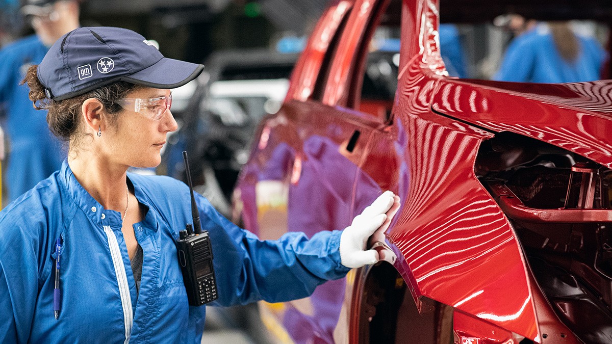 A GM Employee Testing the Smoothness of a GM Vehicle Frame's Exterior