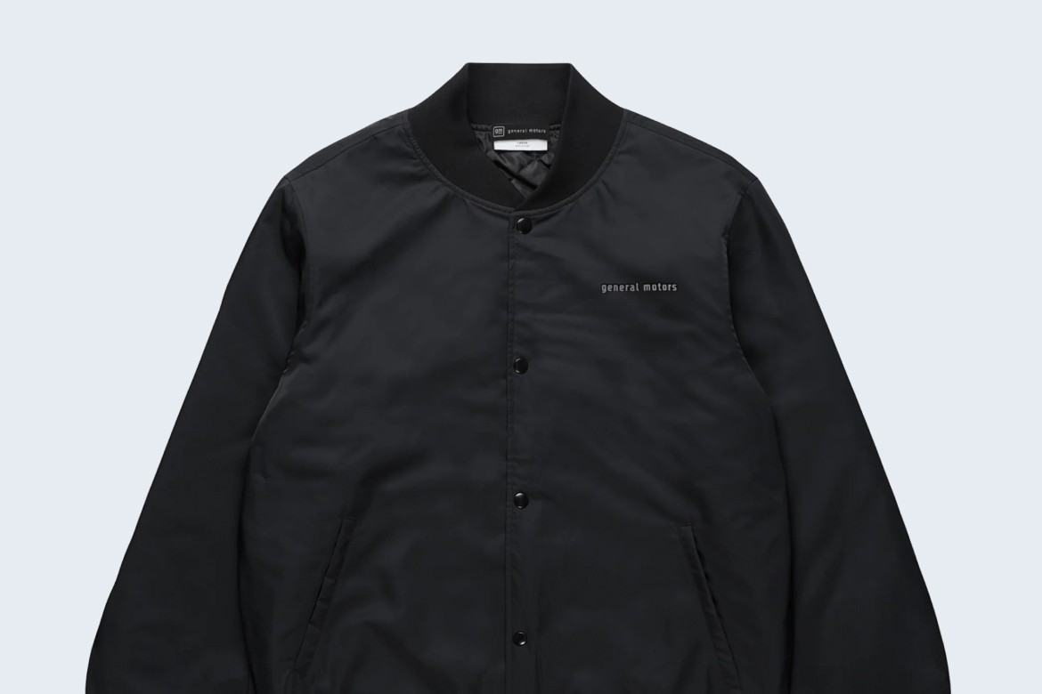 Black Collegiate Bomber Jacket With General Motors Text on Chest with Button-Up Front, Side Pickets, and Ribbed Cuffs.