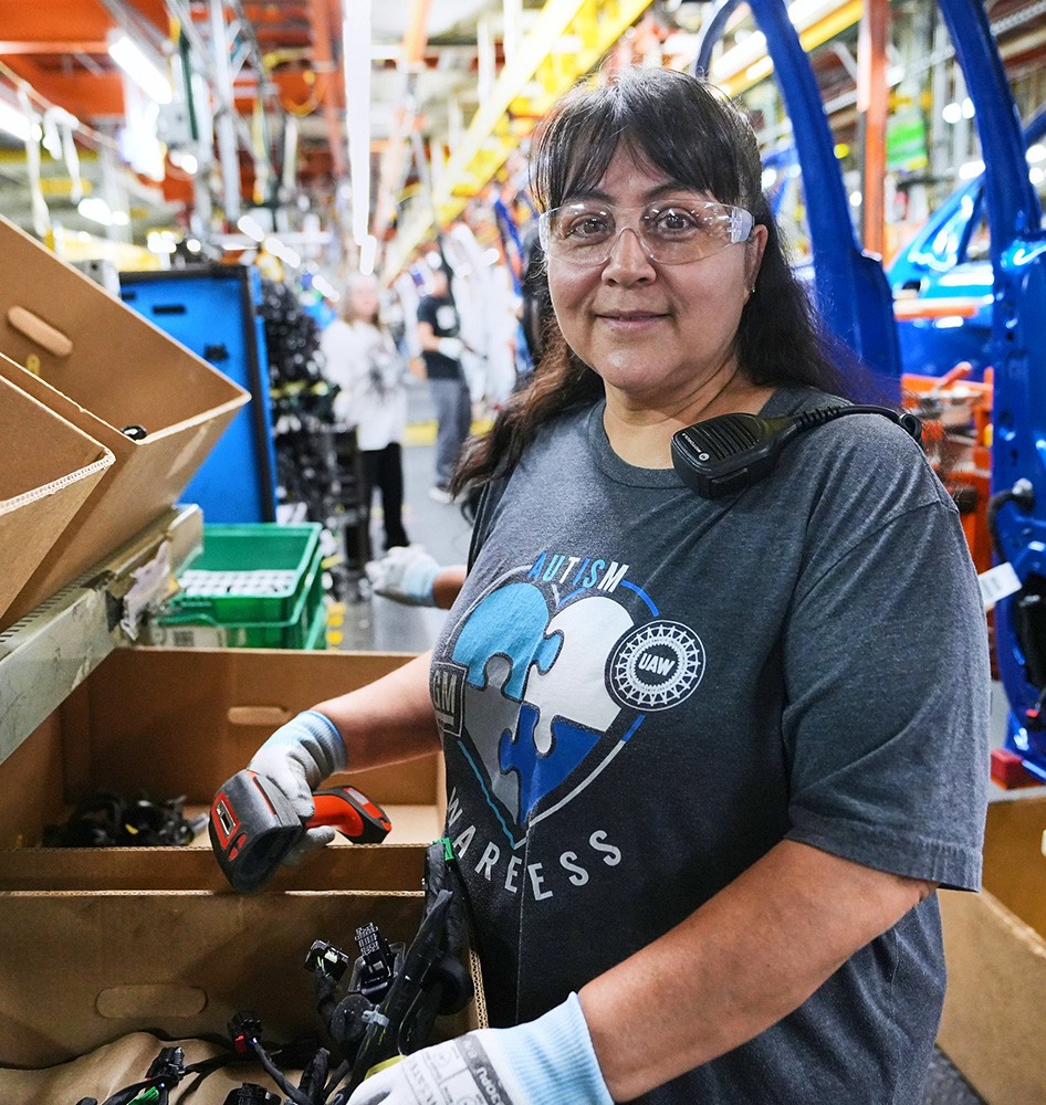 Employee at Fort Wayne Assembly poses in front of door assembly on production line.