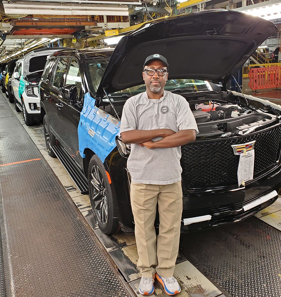 Arlington Assembly employee poses in front of vehicle on assembly line.